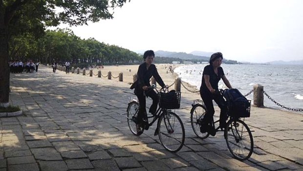 Gearing up for a busy summer: Locals ride on bicycles along a beach in Wonsan, a sleepy port on North Korea's east coast.