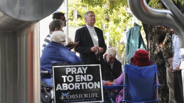 Catholic Archbishop of Canberra and Goulburn Christopher Prowse, centre, attends a prayer vigil outside the ACT Health building in Moore Street, Civic, on Tuesday.