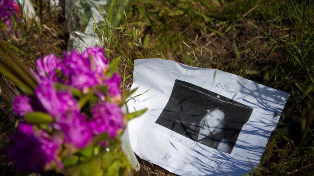 A photo of victim Doris Chibuko rests next to flowers at a memorial in front Oikos University.