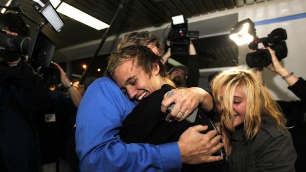 Home safe ... Derrik Sweeney, centre, hugs his father Kevin Sweeney, left, and sister Ashley, right, after arriving in the US on Saturday.