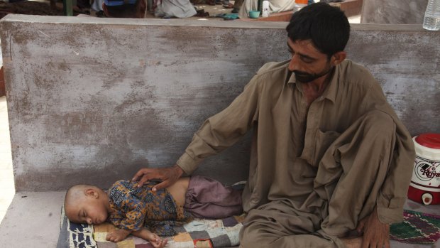 A man with his severely dehydrated daughter waits for a medical help outside a hospital ward in Karachi on Wednesday. 