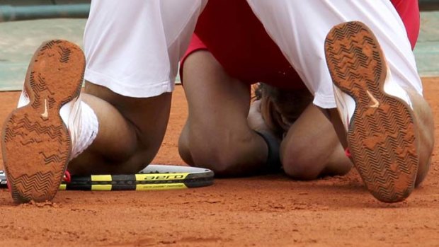Clay king ... Rafel Nadal drops to his knees after defeating Novak Djokovic to secure a record seventh French Open win.