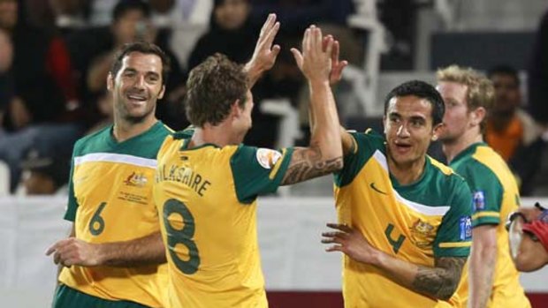 Tim Cahill (right) celebrates his second goal with Sasa Ognenovski (left) and Luke Wilkshire.