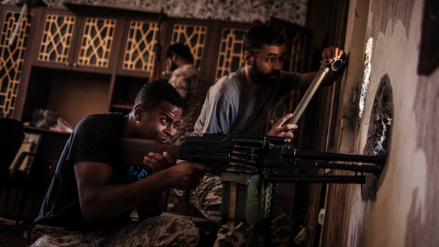 A Libyan fighter affiliated with the Tripoli government searches for sniper positions from a hole in a building on the frontline with Islamic State militants, in Sirte, Libya. 