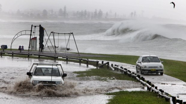 One driver takes on the flooded car park at the Bellambi Pools while another uses the bike track.