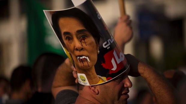 A member of the Islamic Movement in Israel holds a defaced poster of  Aung San Suu Kyi during a demonstration in Tel Aviv.