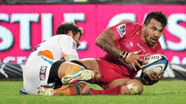 Digby Ioane of the Reds is tackled by Willie le Roux.