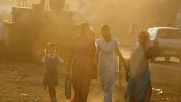 People walk through the haze of an industrial area of Mumbai.