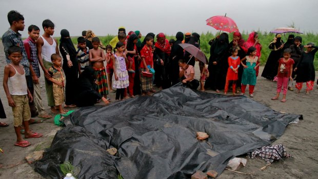 Bangladeshi villagers gather around the covered bodies of Rohingya women and children who died after their boat capsized.