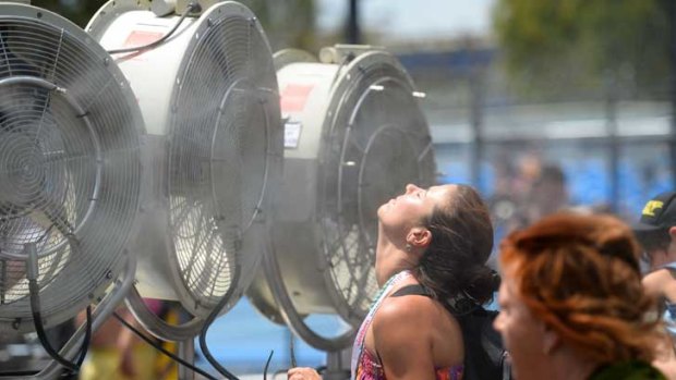 A woman cools off with fans and mist put out for spectators as a heat wave continues to sizzle at the Australian Open on Wednesday.