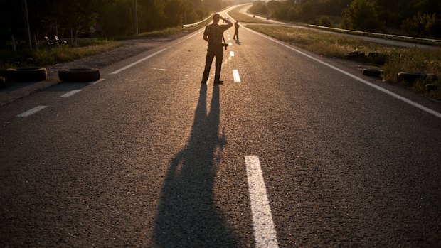 Pro-Russian rebels guard the road as Australian, Malaysian and Dutch investigators continue to examine the area of the downed Malaysia Airlines Flight 17, near the village of Rossipne, Donetsk.