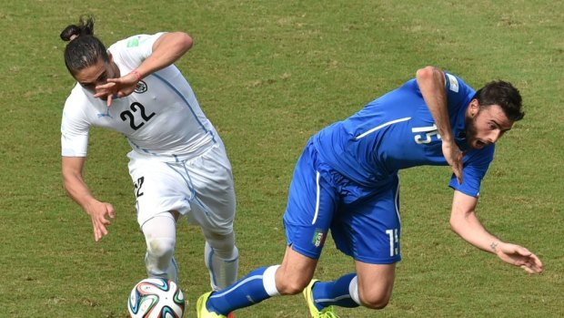 Uruguay’s Martin Caceras sends Italy’s Andrea Barzagli tumbling.