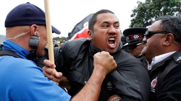 A Maori protester is held back by Maori wardens and police.