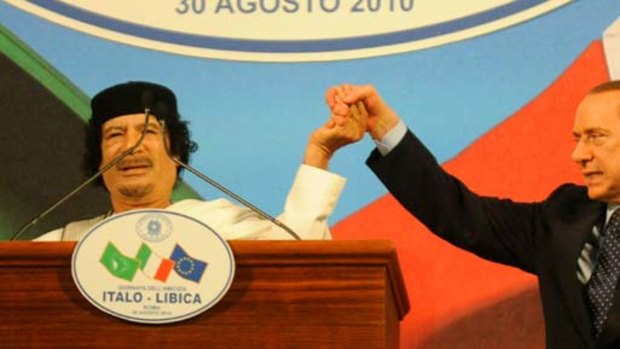 Libyan leader Muammar Gaddafi, left, shakes hands with Italian Prime Minister Silvio Berlusconi