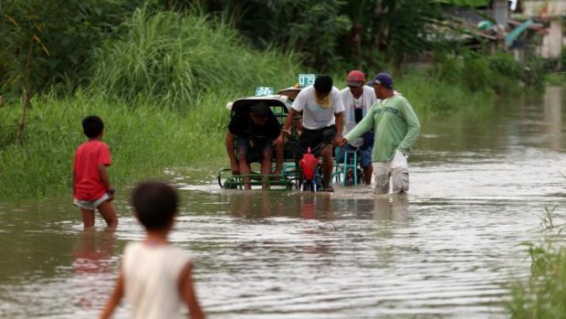 Residents cross a flooded road on in Sultan Kudarat, Mindanao, Philippines. Thousands of people are fleeing the coastal areas.