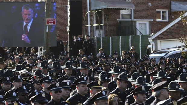 Law enforcement officers turn their backs on a video monitor as New York City Mayor Bill de Blasio speaks during the funeral of slain NYPD officer Rafael Ramos.