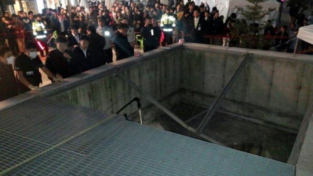 People gather around the collapsed ventilation grate at an outdoor arena in Seongnam, south of Seoul.