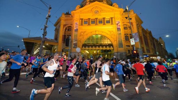 Runners pass Flinders Street Station in the early hours of the morning.