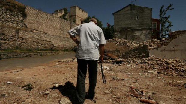 Ergun walks towards his UNESCO-listed home (right) through the debris of demolished neighbouring homes in Istanbul's Sulukule district.
