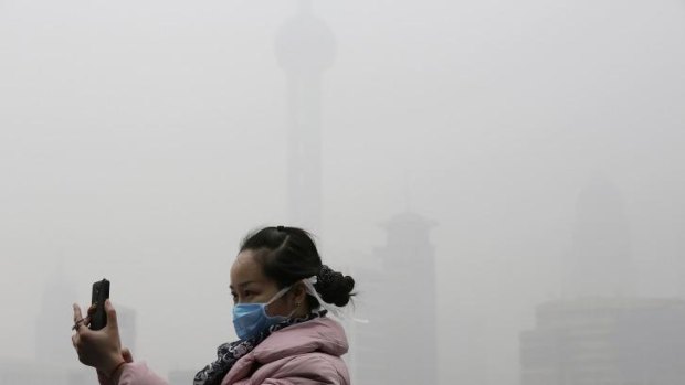 A tourist with a protective mask takes a selfie at the Bund under heavy haze in Shanghai.