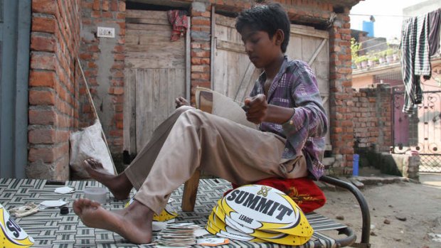 Ramandeep, 13, stitches Summit rugby league balls, bound for Australia, outside his home in Jalandhar, in Punjab in northern India.