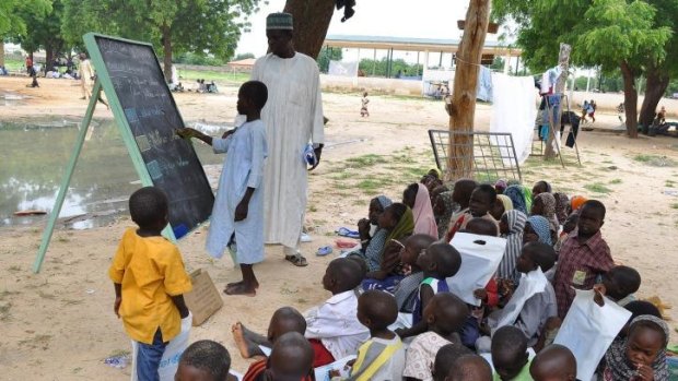 Children who fled their homes following an attack by Islamist militants in Bama, take a lesson at a camp in Maiduguri, Nigeria.