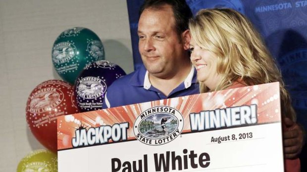 Paul White, of Ham Lake, Minnesota, and his girlfriend Kim VanRees, hold up the winnings about his plans after he was announced as one of the winners of the $US448.4 million Powerball Jackpot.