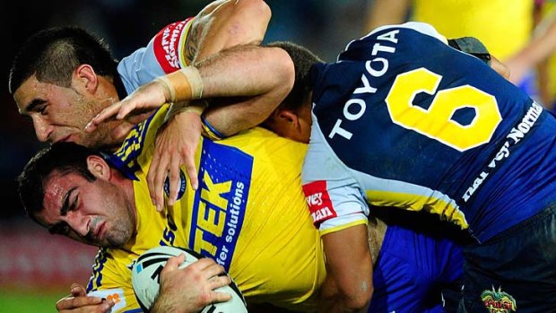 Tim Mannah of the Eels is tackled by James Tamou and Ray Thompson of the Cowboys.