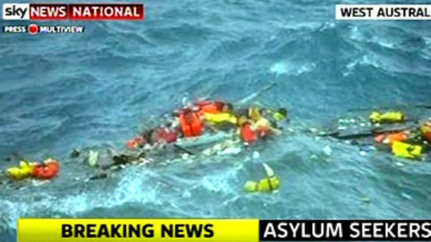 Asylum seekers struggle to cling to wreckage in huge seas off Christmas Island.