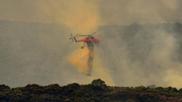 A helicopter dumps water on a fire at Bunyip State Forest.