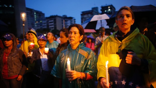 Women hold candles during a vigil to honor the more than 90 people killed during three months of anti-government protests in Caracas, Venezuela on Thursday.