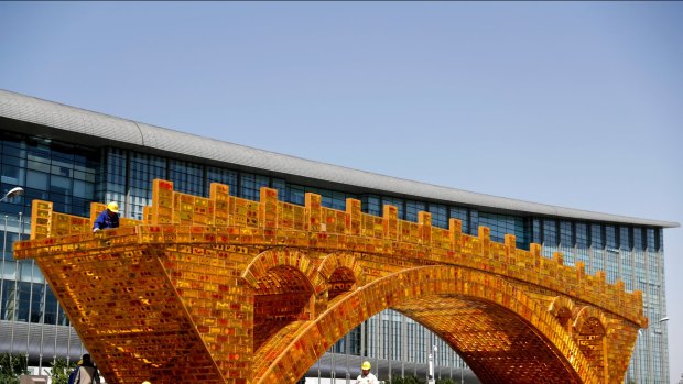 Workers install a 'Golden Bridge of Silk Road' structure outside revealed at the time of China's Belt and Road Forum in Beijing in April.