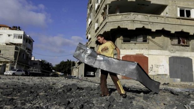A Palestinian man carries a metal sheet near a Hamas training camp following an Israeli air strike on it in Gaza City.
