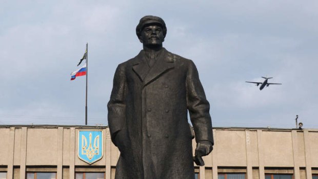 A military plane flies over a statue of Lenin in front on administration building seized by pro-Russian miltias in the eastern Ukrainian city of Slavyansk.