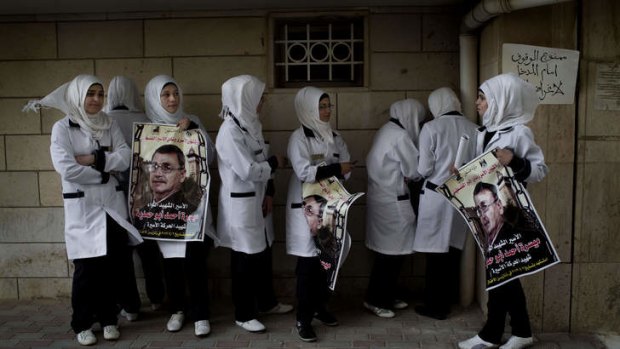 Palestinian nurses hold posters with the picture of Maysara Abu Hamdiyeh, a prisoner who died of cancer in an Israeli jail.