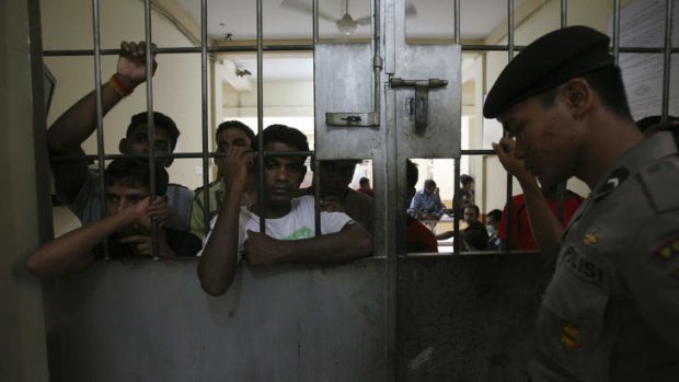 Migrants look out from bars at a cell of an immigration detention center in Belawan, North Sumatra, Indonesia