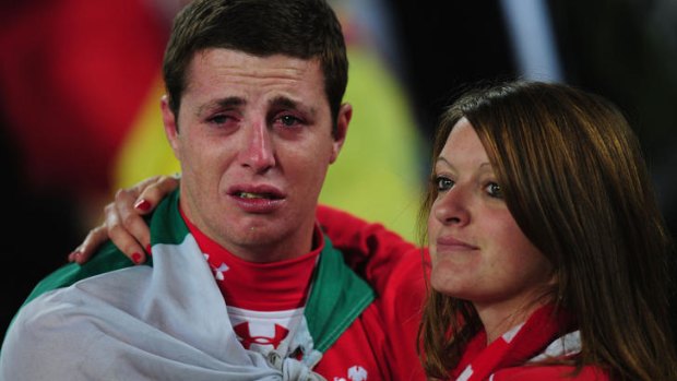 Dejected Wales fans console each other following their team's 9-8 defeat.