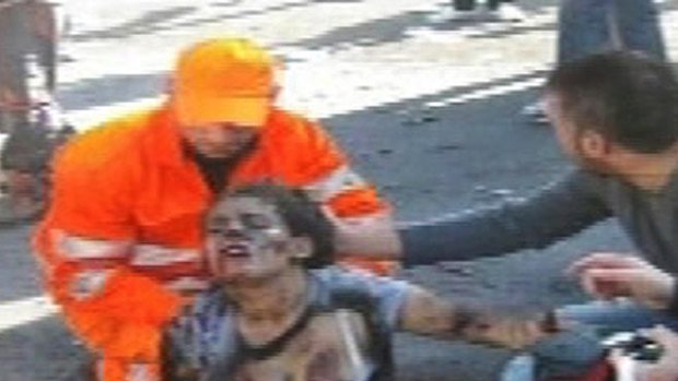 A victim of the bombing is helped in this screen grab from a live TV report.