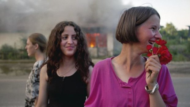Ethnic Albanian Kosovar girls celebrate freedom in front of a burning house.