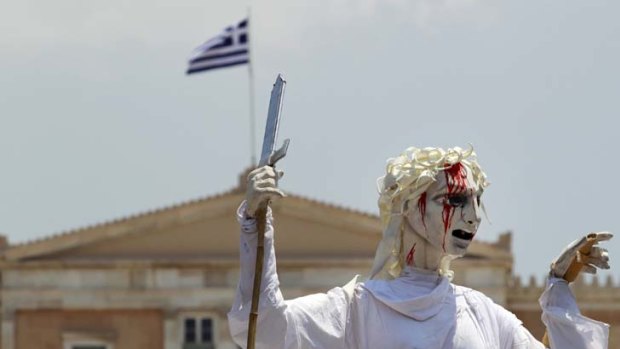 Jobs injustice ... performers from the French theatrical company Le Theatre du Soleil hold up a giant marionette of ‘‘Justice’’ with a bloodied face during a rally against austerity measures in Syntagma Square in central Athens.
