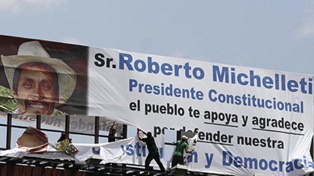 Fighting on ... supporters of Manuel Zelaya rip down a billboard thanking the new president, Roberto Micheletti, for "defending our democracy".