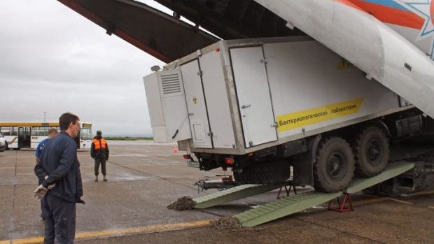 A truck with a mobile lab, right, to be used on Ebola-related treatment, given by the Russians, is offloaded at the airport in Conakry, Guinea.