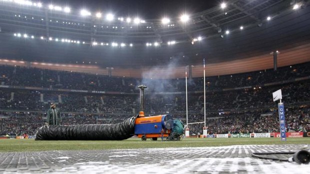 Workers try to defrost the pitch of the Stade de France.