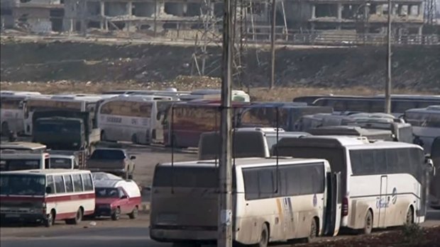In this still image taken from video from Syria TV vehicles wait to cross into east Aleppo at Ramouseh crossing point, Sunday, Dec. 18, 2016. (Syria TV via AP) 