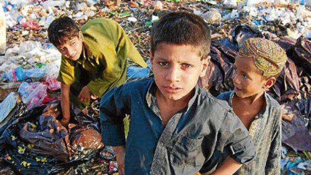 Afghan refugees search for scraps in a Pakistan refugee slum.