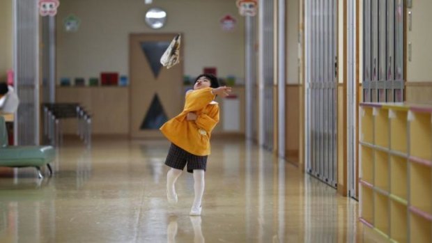 A child plays with a paper plane at the corridor of the Emporium Kindergarten in Koriyama.