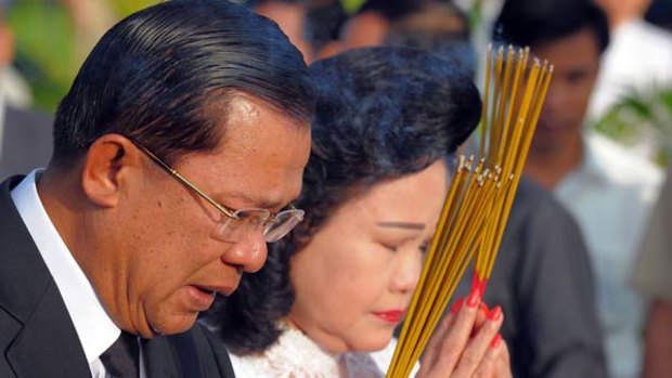 Paying their respects ... Hun Sen and his wife Bun Rany pray while holding burning incense sticks at the mourning ceremony.