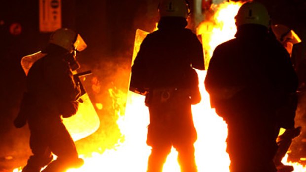 A petrol bomb explodes in front of police during riots in Athens.