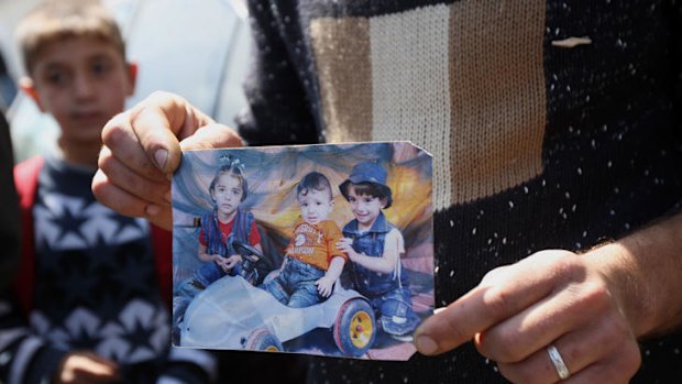 A mourner holds a photo of the three dead Bashir children.