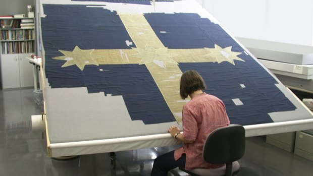 Textile conservator Kristin Phillips works on the Eureka flag, which has suffered considerable damage over the years.